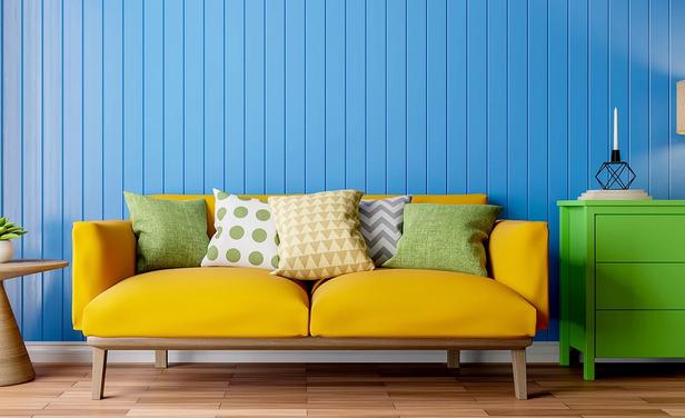 apartment with bright blue wall, yellow couch and green dresser