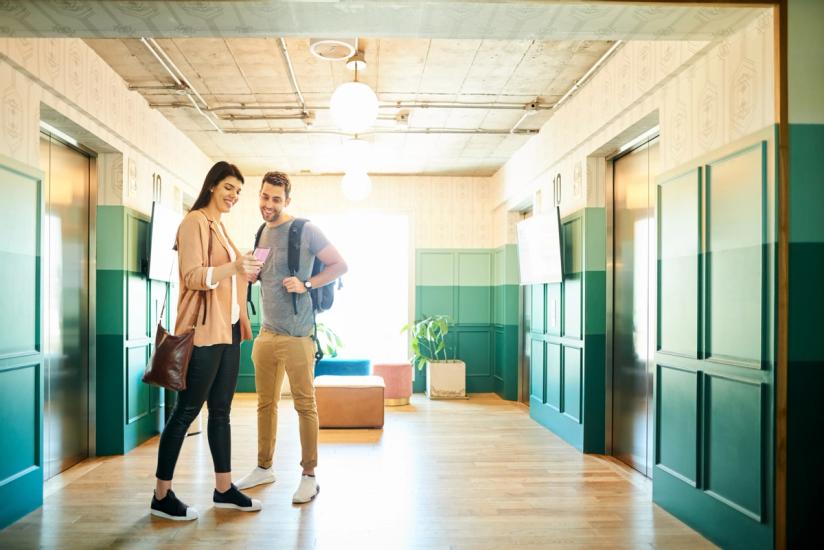 Couple looking at phone by apartment elevators