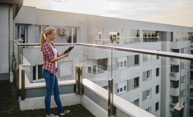 woman looking at tablet on apartment balcony