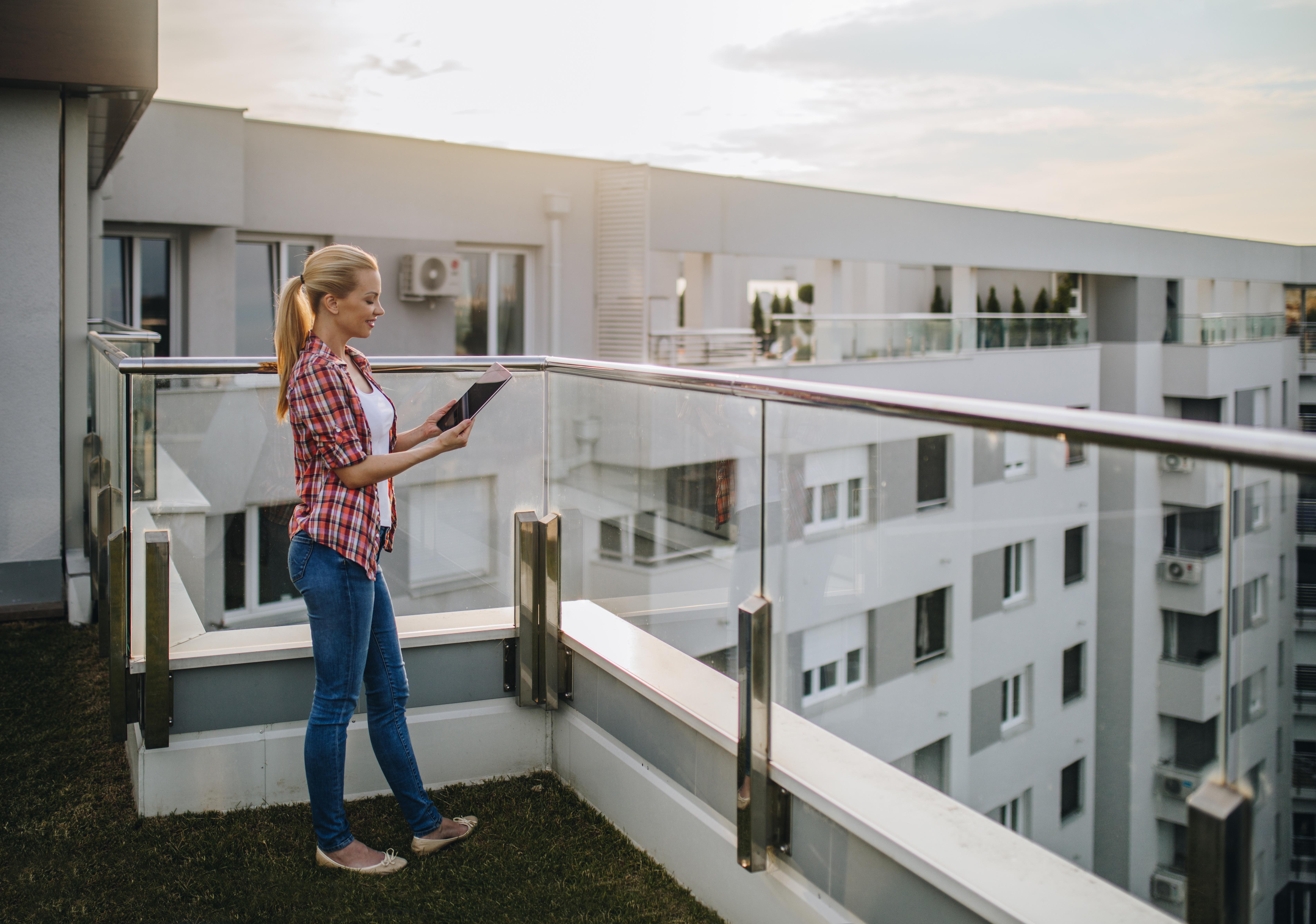 woman looking at tablet on apartment balcony