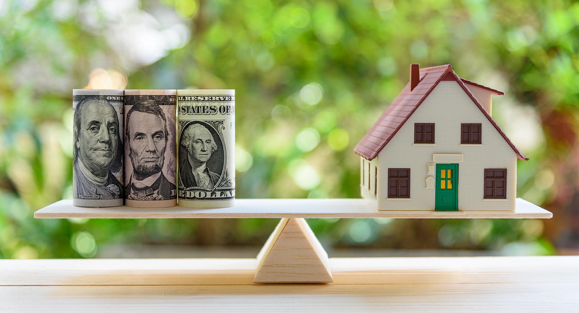 money and house balancing on teeter totter 