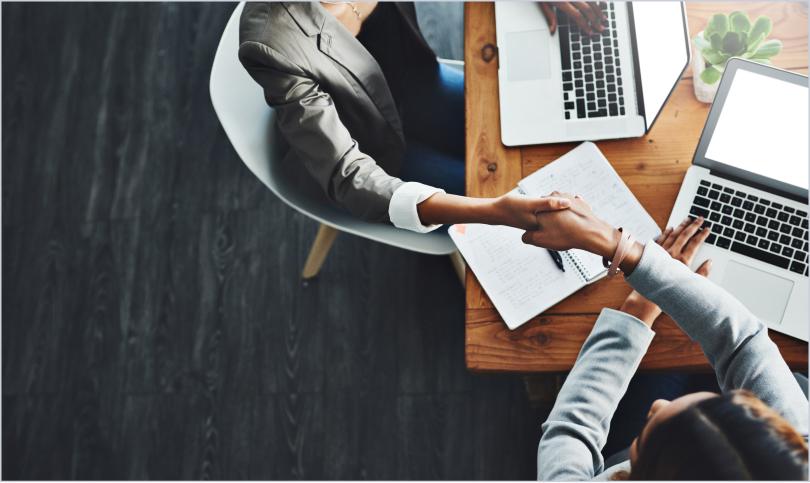 two people at work station shaking hands
