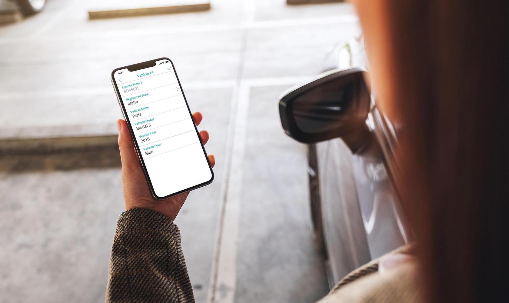 SmartRent user holds a smartphone with parking information displayed on the screen.