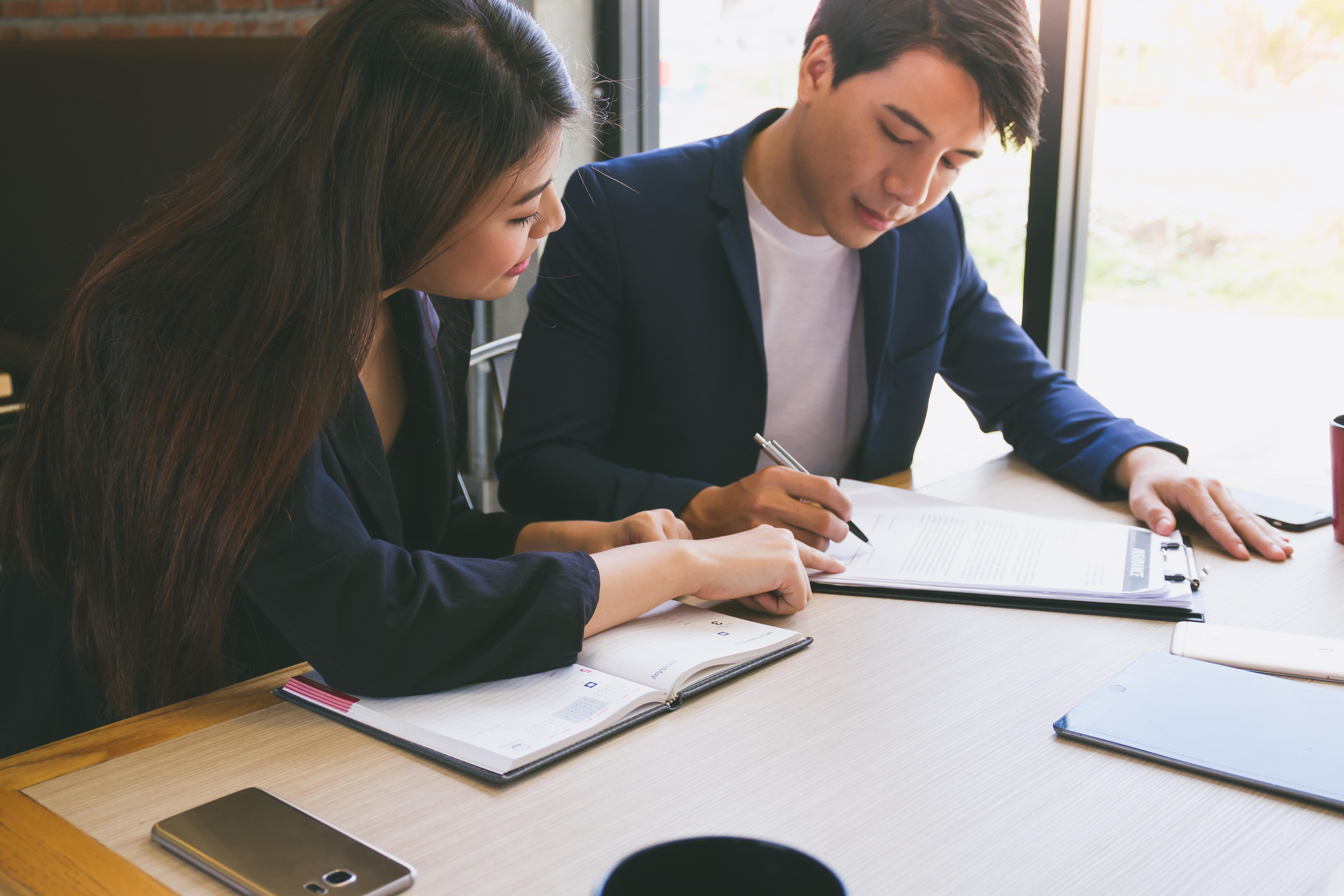 two people looking a documents on a desk together