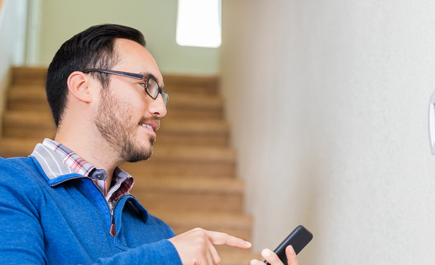 Resident uses smartphone to control a thermostat.